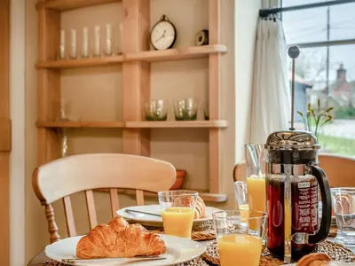 a table topped with plates of food and orange juice at Hill Farm in Blyford