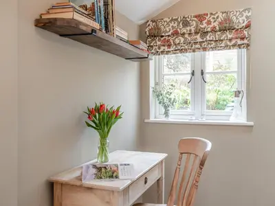 a dining room table with a vase of flowers and a window at Hill Farm in Blyford