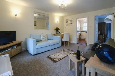 a living room with a blue couch and a television at 1 Coastguard Court in Aldeburgh