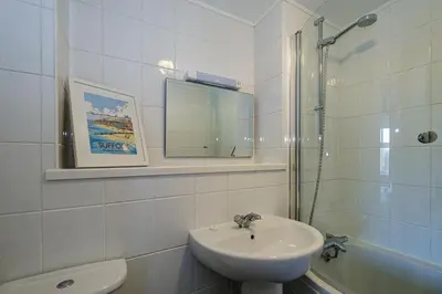 a white bathroom with a sink and a shower at 1 Coastguard Court in Aldeburgh