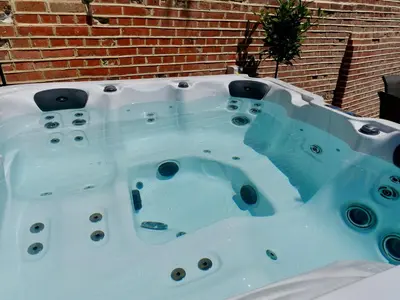 a jacuzzi tub in front of a brick wall at Luxury 9 Bed Manor House Hot Tub Cinema Room SkyTV in Saffron Walden