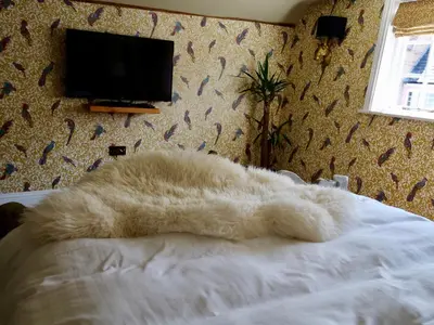 a white blanket laying on a bed in a bedroom at Luxury 9 Bed Manor House Hot Tub Cinema Room SkyTV in Saffron Walden