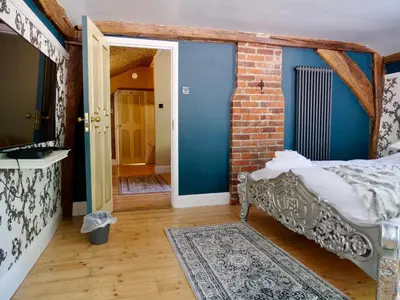 a room with a bed and a brick wall at Luxury 9 Bed Manor House Hot Tub Cinema Room SkyTV in Saffron Walden