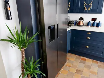 a kitchen with blue cabinets and a potted plant at Luxury 9 Bed Manor House Hot Tub Cinema Room SkyTV in Saffron Walden