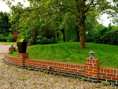 a brick wall with a vase in a park at Deluxe 4 5 Bed Hot Tub Cinema Room 15 in Saffron Walden