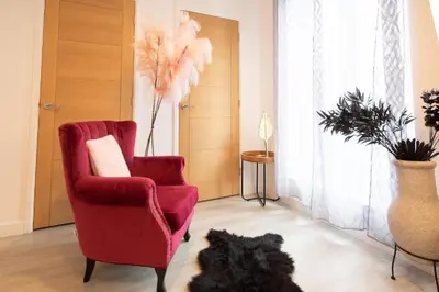 a black dog laying in a living room with a red chair at Modern Pet-Friendly Apartment in Cambridge with Garden & Parking in Chesterton