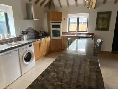 a kitchen with a washing machine and a washer at Wood Farm Barn in Laxfield