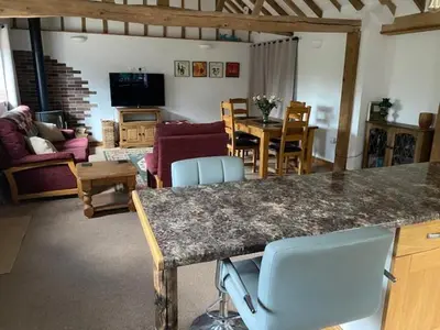 a kitchen and living room with a table and chairs at Wood Farm Barn in Laxfield