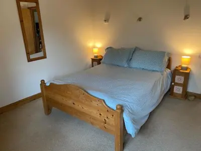 a bedroom with a bed with two lamps on two tables at Wood Farm Barn in Laxfield