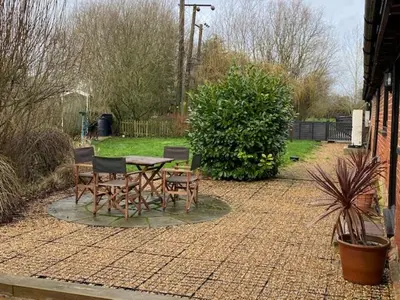 a patio with a table and chairs in a yard at Wood Farm Barn in Laxfield