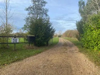 a dirt road with a sign on a fence at Wood Farm Barn in Laxfield