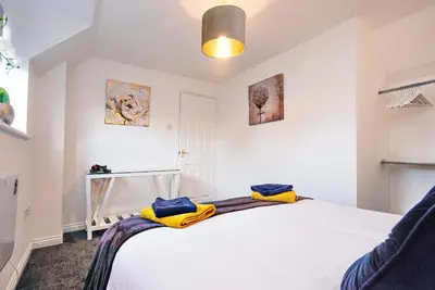 a bedroom with a white bed with yellow towels on it at Victoria Gardens in Colchester