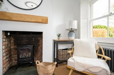 a living room with a chair and a fireplace at 3 Lower Falkland Cottage Long Melford in Sudbury
