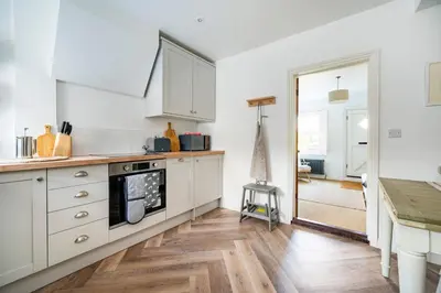 a kitchen with white cabinets and a wooden floor at 3 Lower Falkland Cottage Long Melford in Sudbury