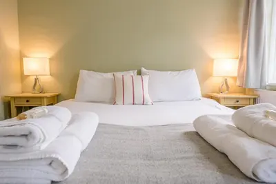 a bedroom with a white bed with towels on it at Pelican Cottage, Aldeburgh in Aldeburgh