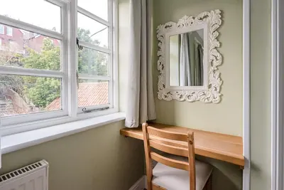 a mirror sitting on a wall next to a chair next to a window at Pelican Cottage, Aldeburgh in Aldeburgh