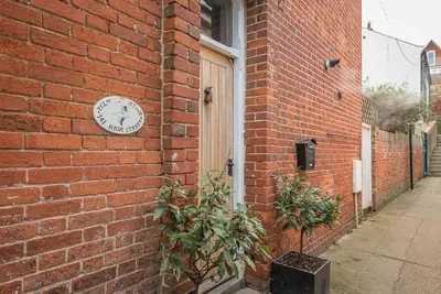 a clock on the side of a brick building at Pelican Cottage, Aldeburgh in Aldeburgh