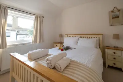a bedroom with a white bed with towels on it at The Pink House, Aldeburgh in Aldeburgh