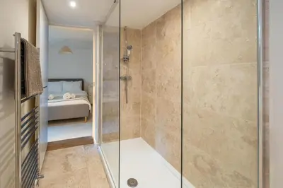 a shower with a glass door in a bathroom at The Pink House, Aldeburgh in Aldeburgh