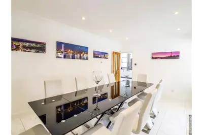 a dining room with a glass table and white chairs at 6BD Vacation Home with Indoor Pool in Canvey Island