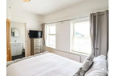 a bedroom with a bed and a tv and two windows at 6BD Vacation Home with Indoor Pool in Canvey Island