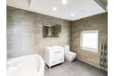 a bathroom with a tub and a toilet and a sink at 6BD Vacation Home with Indoor Pool in Canvey Island