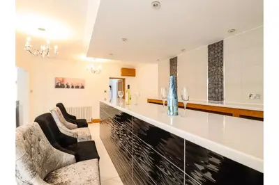 a kitchen and living room with two chairs and a counter at 6BD Vacation Home with Indoor Pool in Canvey Island