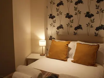 a bedroom with a bed with orange pillows and a lamp at Painters at the Angel in Sudbury
