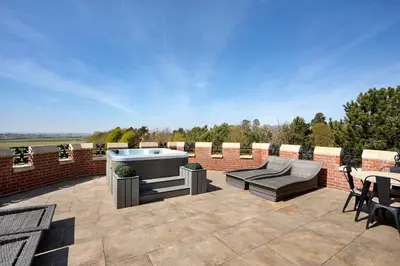 a patio with a hot tub and tables and chairs at South Lodge, St Osyth Priory in Saint Osyth