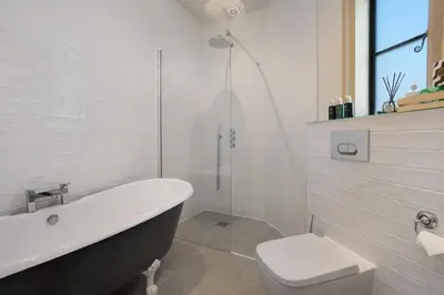 a white bathroom with a tub and a toilet at South Lodge, St Osyth Priory in Saint Osyth
