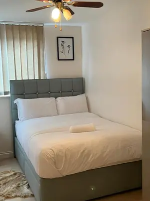 a bed in a bedroom with a ceiling fan at Next-Stop Haven in Harlow