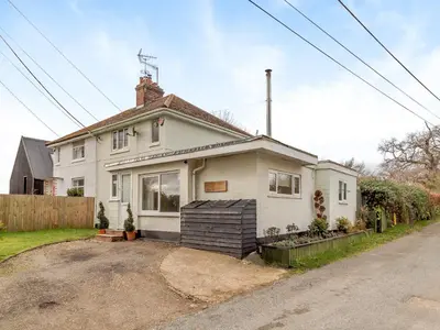 a white house with a fence in front of it at Oak Cottage in Saxmundham