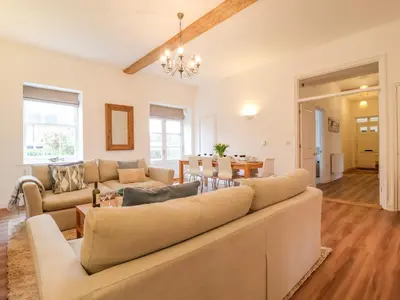 a living room with a large couch and a dining room at Feathers, Blythburgh in Halesworth