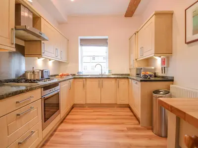a kitchen with wooden cabinets and a wooden floor at Feathers, Blythburgh in Halesworth
