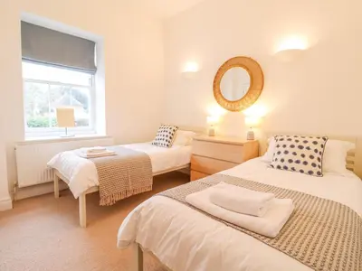 a bedroom with two beds and a mirror at Feathers, Blythburgh in Halesworth