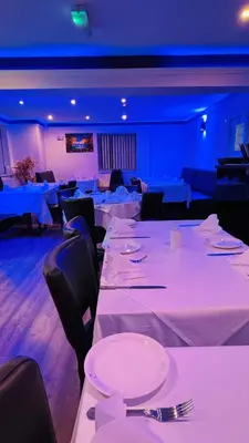 a dining room with white tables and chairs and blue lighting at White House Lodge in Cambridge