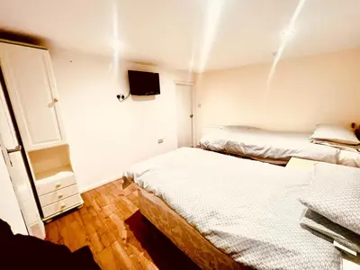 a bedroom with two beds and a tv on the wall at White House Lodge in Cambridge