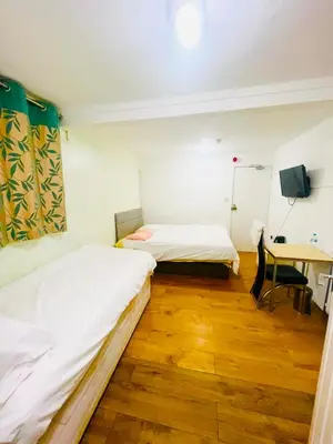 two beds in a room with a table and a desk at White House Lodge in Cambridge