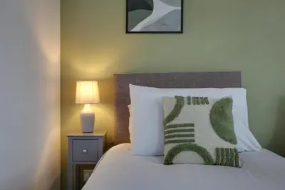 a bed with a green and white pillow on it at Entire home/flat perfect for contractors in Bishops Stortford