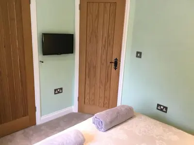 a bedroom with a bed and a television on the wall at Beautifully appointed & cosy self contained annexe in Walsham le Willows