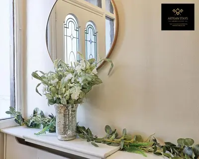 a vase of flowers on a shelf in front of a mirror at Spacious 3 Bedroom and 2 Bathroom in Southend-on-Sea By Artisan Stays I Weekly or Monthly Stay Offer I Free Parking I Sleeps 7 in Southend-on-Sea