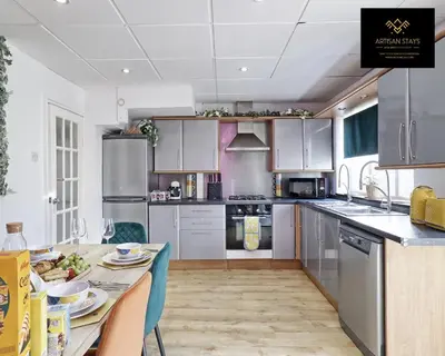 a kitchen with stainless steel appliances and a table at Spacious 3 Bedroom and 2 Bathroom in Southend-on-Sea By Artisan Stays I Weekly or Monthly Stay Offer I Free Parking I Sleeps 7 in Southend-on-Sea