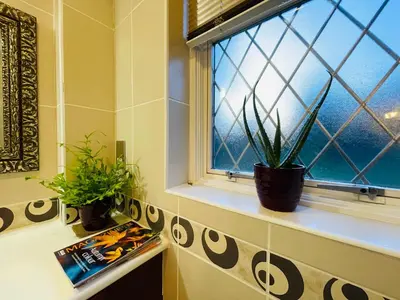 a bathroom window with two potted plants on a shelf at Super King Bed Suite, Executive office, fast WiFi, free parking in St Ives