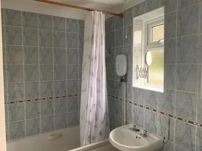 a bathroom with a sink and a shower curtain at St Ives, King Bed Cosy home, parking, fast Wi Fi in St Ives
