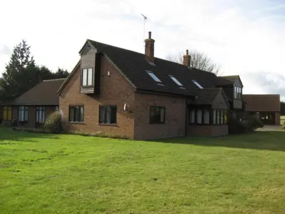 a large brick house with a green yard in front of it at Clare House in Mundford