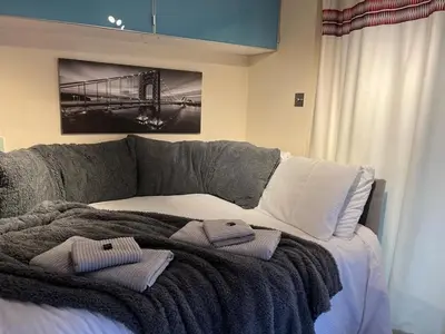 a bed with a blanket and two towels on it at Studio Annex in Cottenham