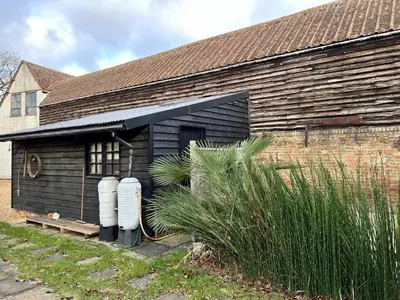 an old wooden building with a large window at Studio Annex in Cottenham