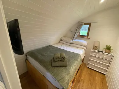 a small bedroom with a bed with a hat on it at Wimbish Hall Cabins in Wimbish