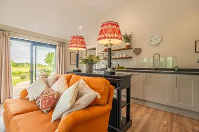 a living room with an orange couch and a kitchen at Elegant luxurious cottage - The Dove House in Ipswich