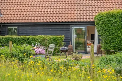a garden with a table and chairs in front of a house at Elegant luxurious cottage - The Dove House in Ipswich